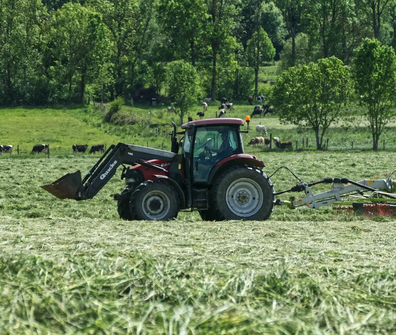 red tractor with farming attachment on field during daytime